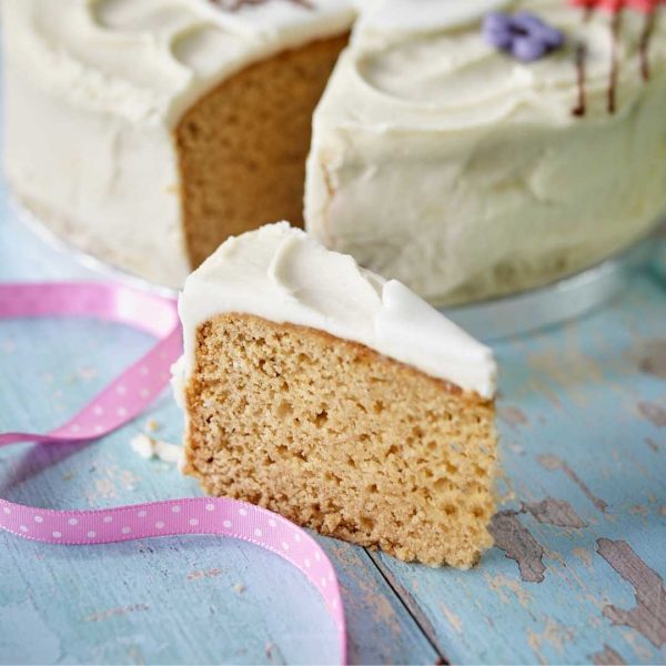 A vegan lemon cake slice with pink ribbon, topped with zesty lemon frosting.